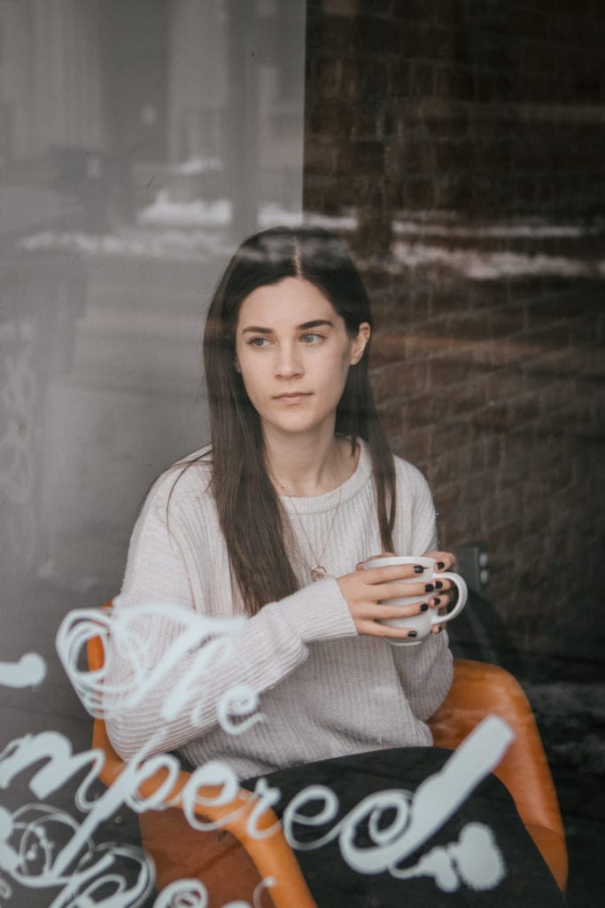 Girl holding a cup of coffee looking out the window