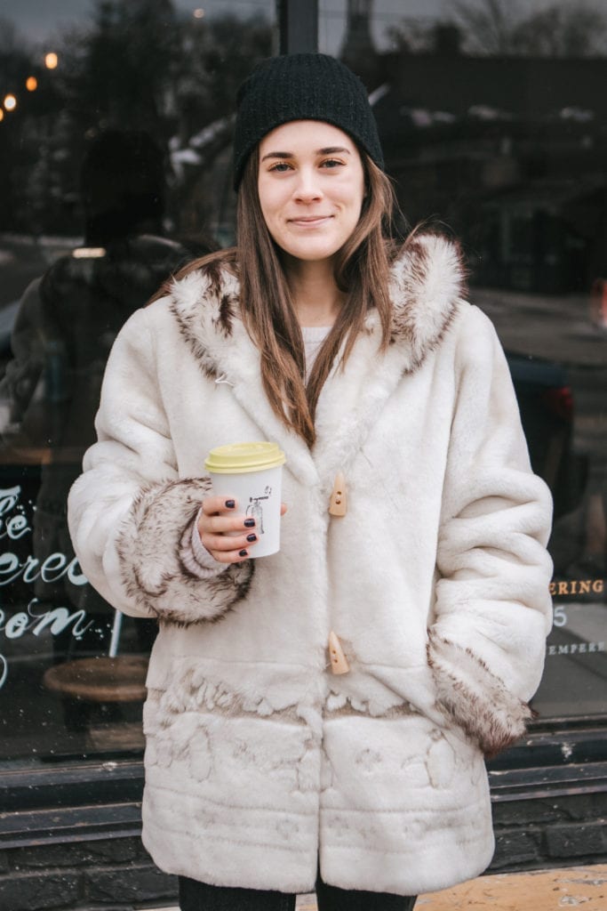 Girl standing in front of coffee shop holding coffee